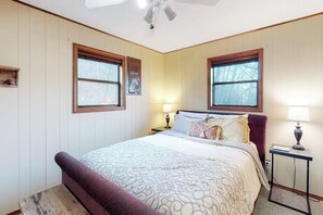 Een slaapkamer met een bed, twee bedlampen, een nachtkastje en een plafondventilator.