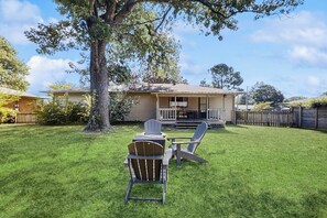 A house with a front porch, a lawn, and two Adirondack chairs. - Large 3BR - Balcony - Firepit - Garage Parking (Bentonville)