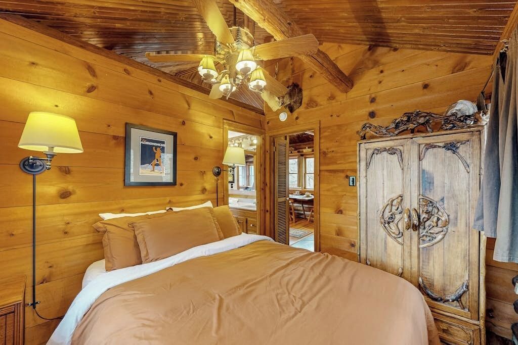 Ein Zimmer in einer Holzhütte mit einem Bett, einem Deckenventilator und einem Kleiderschrank.