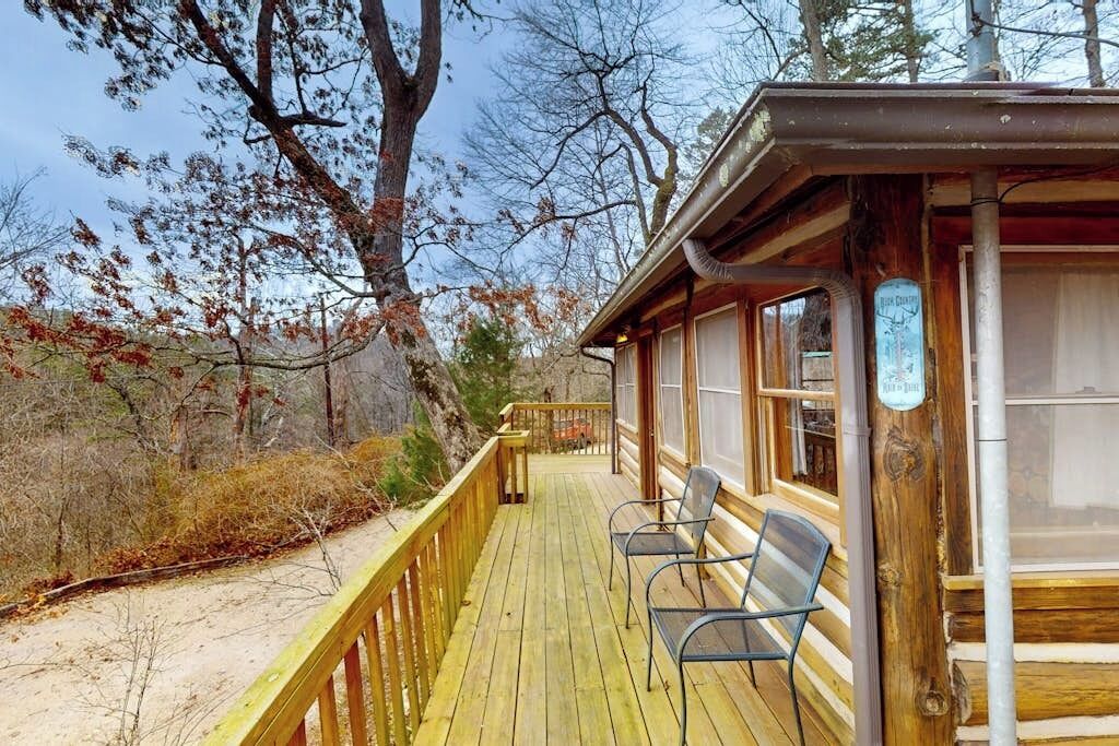 Una cabana de fusta amb una terrassa, dues cadires i un senyal que indica una habitació de lloguer.