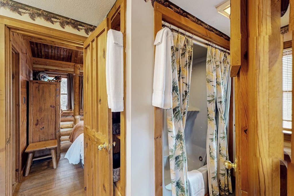 A wooden interior with a shower area, a wooden bench, and a door with a towel hanging on it.
