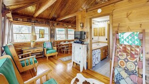Ein Holzhütten-Interieur mit Essbereich, Sitzgelegenheiten und einem Fernseher.