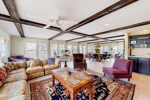 A spacious living area with a large sofa set, a coffee table, and a red armchair. There is a dining area with a table and chairs, and a kitchen with dark cabinetry. - Spacious 5BR - Fireplace - Deck - Firepit (Eureka Springs)