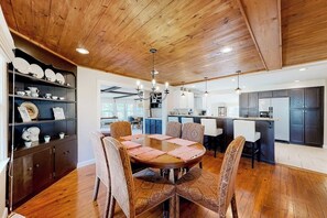 A dining area with a round table, chairs, and a wooden ceiling. - Spacious 5BR - Fireplace - Deck - Firepit (Eureka Springs)