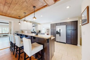 A modern kitchen with a central island, bar stools, and dark cabinetry. - Spacious 5BR - Fireplace - Deck - Firepit (Eureka Springs)