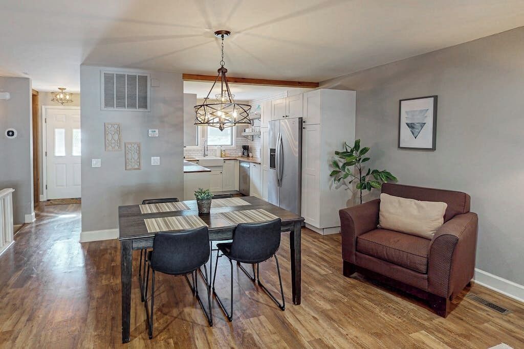 A dining area with a wooden table and chairs, a brown sofa, and a kitchen in the background.