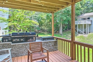 Eine Terrasse im Freien mit Steinmauer, Grill und Holzstuhl.