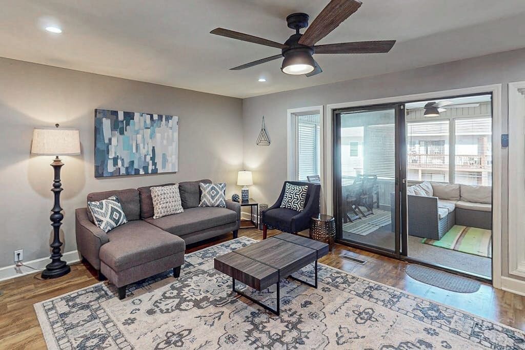 A living room with a sofa, armchair, coffee table, and a ceiling fan.