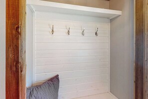Eine weiße Holzwand mit einer Reihe Haken und einem Kissen.