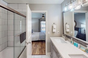 Een badkamer met een douche, wastafel en spiegel.