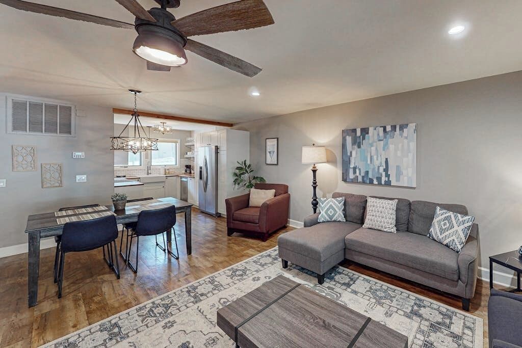 A living room with a sofa, coffee table, and a dining area with chairs and a table.