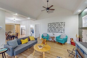 A spacious living room with a grey sofa, teal armchairs, and a wooden coffee table. - Whispering Trails | Bike-In/Bike-Out Retreat (Bentonville)