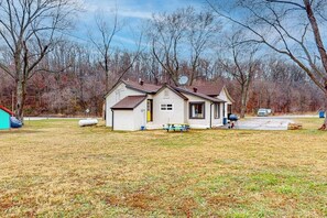 A single-story house with a sloped roof, a satellite dish, and a small deck. - Whispering Trails | Bike-In/Bike-Out Retreat (Bentonville)