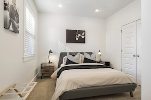 Ein Schlafzimmer mit einem Bett, Nachttischen, einem Wandbild und einer Tür.
