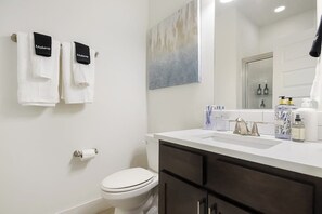 Une salle de bain équipée de toilettes, d’un lavabo avec des articles de toilette et de serviettes suspendues sur un porte-serviettes.