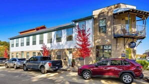A building with a flat facade, multiple windows, and a balcony on the upper floor. - Stylish 2BR -  W&D - Downtown Location (Bentonville)