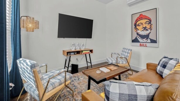 Un salon moderne comprenant un téléviseur à écran plat, un canapé, deux fauteuils, une table basse et une bibliothèque.