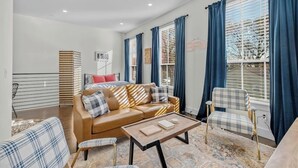 Un salon moderne avec un canapé, des fauteuils, une table basse et un tapis à motifs.