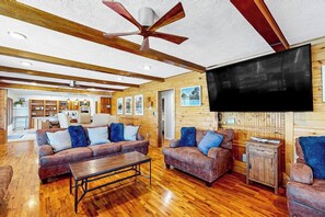 A spacious living room with wooden floors, leather sofas, a coffee table, and a ceiling fan. - 7BR Lakefront Dog Friendly - Private Pool (Garfield)