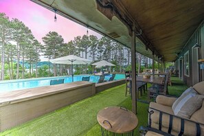 An outdoor pool area with a covered patio, lounge chairs, and a table. - 7BR Lakefront Dog Friendly - Private Pool (Garfield)