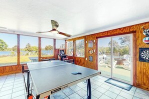A ping pong table in a room with large windows, a ceiling fan, and a dartboard. - 7BR Lakefront Dog Friendly - Private Pool (Garfield)