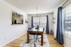 Un comedor con una mesa de madera, sillas azules, una alfombra y una lámpara colgante.