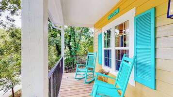 A porch with a wooden railing, two rocking chairs, and a window with shutters.