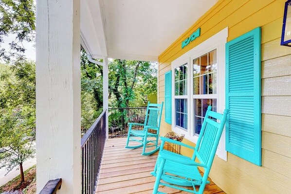 A porch with a wooden railing, two rocking chairs, and a window with shutters. - 2BR New Orleans-themed getaway with a full kitchen (Eureka Springs)