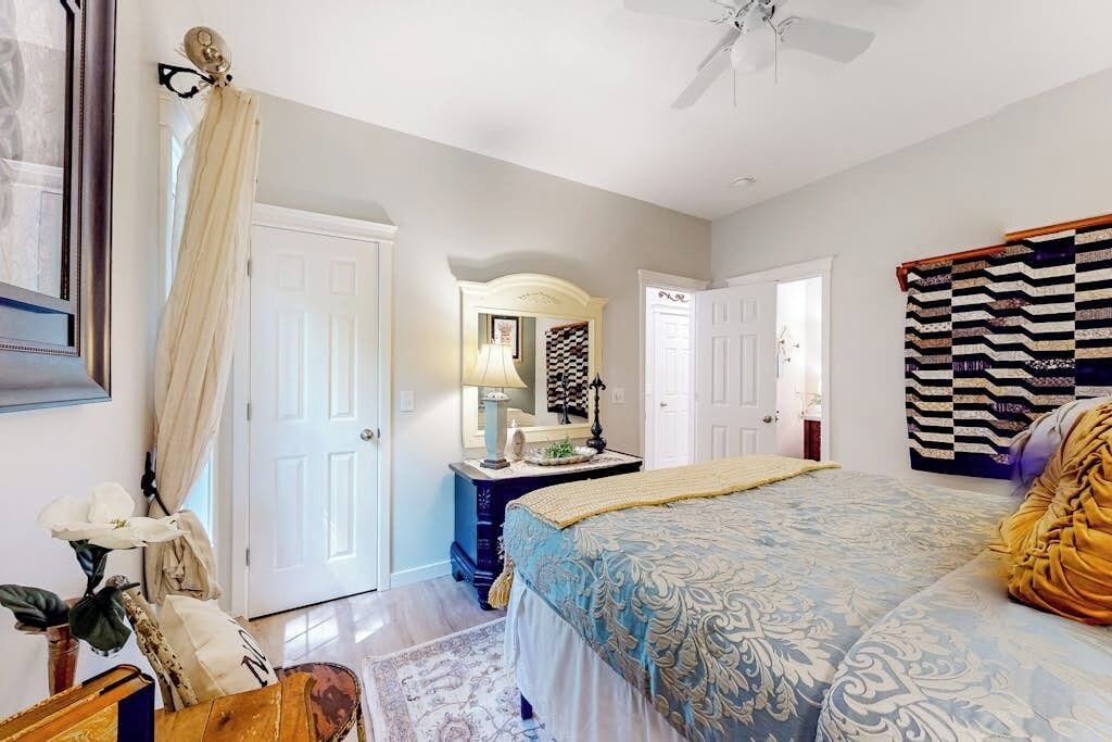 A bedroom with a bed, a dresser, a mirror, and a ceiling fan.