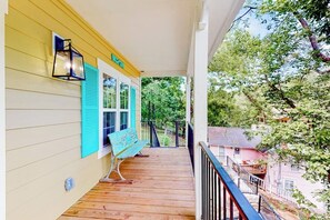 A wooden porch with a bench, a lantern, and a railing.