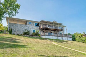 A two-story house with a stone facade, a balcony on the upper floor, and a sloped roof. - 5BR Spacious Lakefront Home with Game Room (Hot Springs)