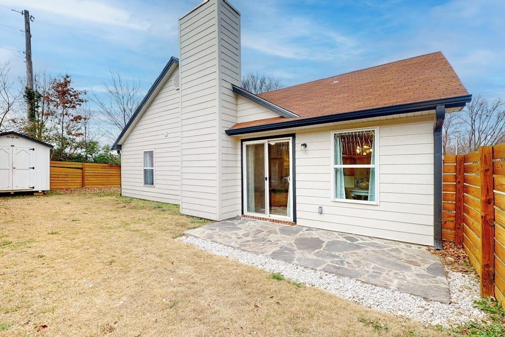 A single-story house with a stone patio, a garage, and a wooden fence.