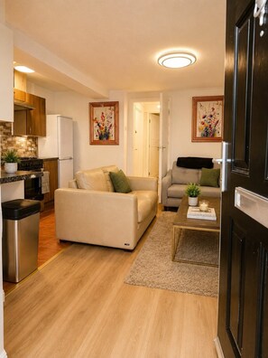 A compact living space with a kitchenette, two sofas, a coffee table, and a door. - Sidemersey Livings- The Parkside Haven (Liverpool)