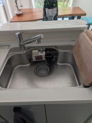 A kitchen sink with a faucet, a soap dish, and a sponge holder.