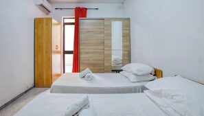 Une chambre d’hôtel avec deux lits, une armoire et un rideau rouge.