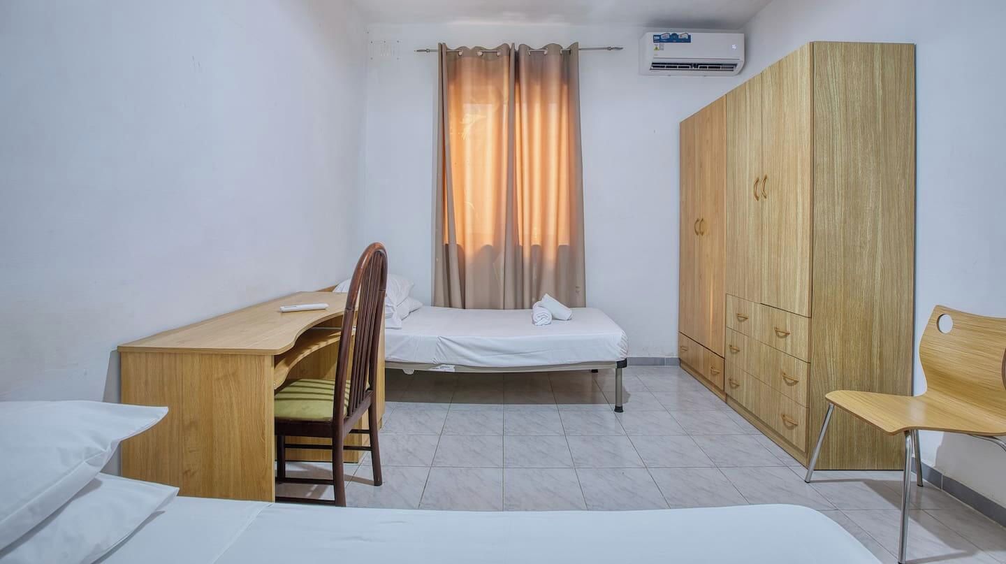 A compact room with a bed, a desk, a chair, and a wardrobe.