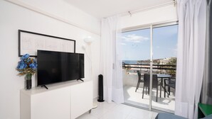 A modern living room with a flat-screen TV, a small table, and a sofa.