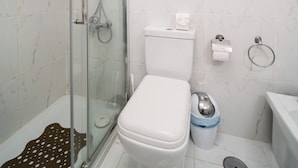 A bathroom with a glass-enclosed shower, a toilet, a bidet, and a sink.
