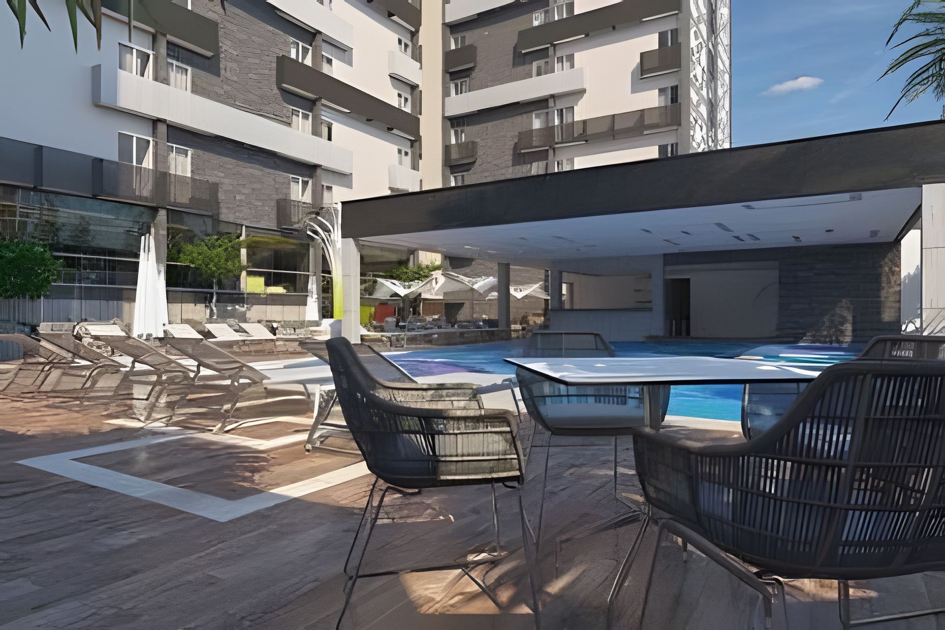 An outdoor swimming pool area with lounge chairs and a covered seating area.