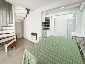 Una habitación con cama, una mesa de comedor, una zona de cocina y una escalera.