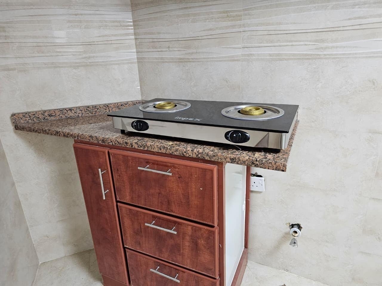 Een keuken met een granieten aanrecht, een ingebouwde kookplaat en houten keukenkastjes.