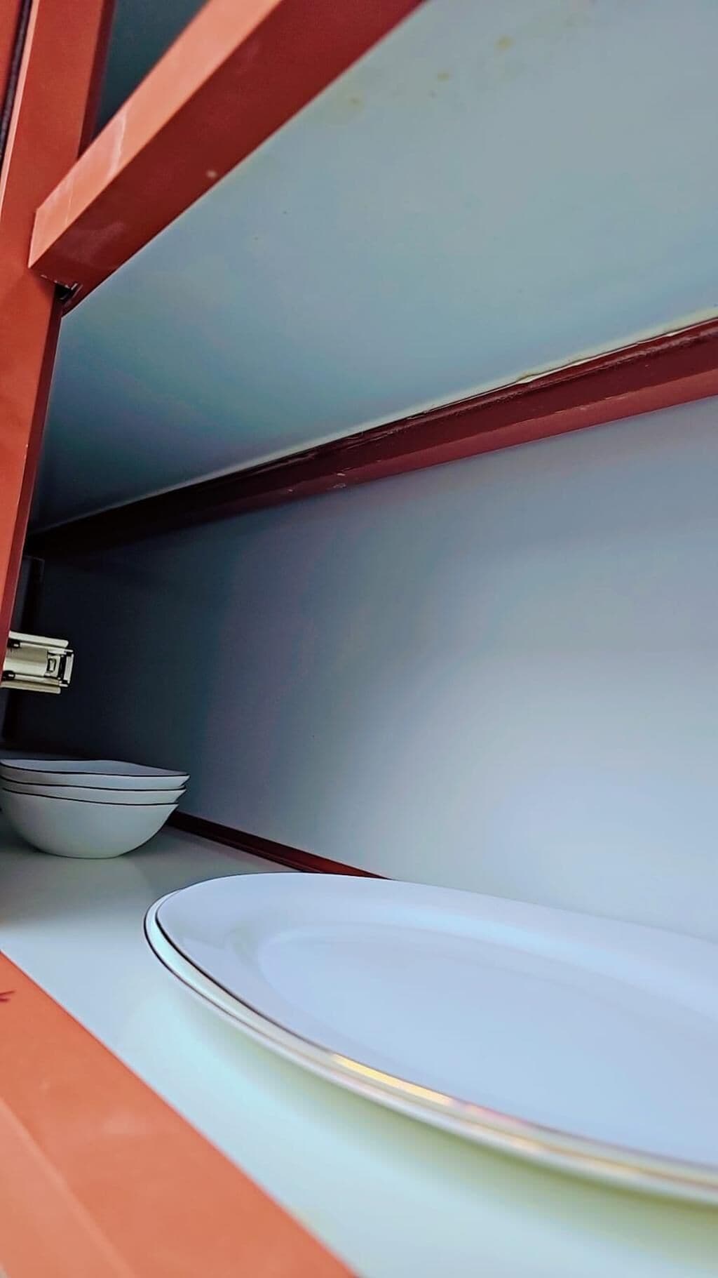 An interior view of a room with a white plate on a counter and a stack of white bowls in the background.
