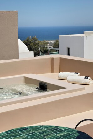 Eine Dachterrasse mit Whirlpool, zwei Handtüchern und Blick auf das Meer.