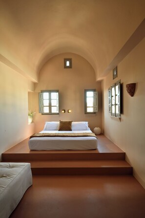 Ein Schlafzimmer mit einem Bett, einem kleinen Fenster und einer Wandleuchte.