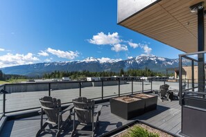 A rooftop terrace with seating and a fire pit, overlooking a mountain range. - Rest & Roam (Revelstoke)