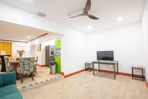 A living room with a sofa, a dining area with chairs, a television, and a ceiling fan. - Spacious 4-Bedroom Miami Home for Group Stays & Gatherings (Miami)