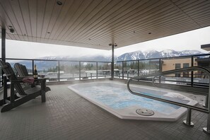 A hot tub on a balcony with a view of snow-capped mountains. - Mountain Magic (Revelstoke)
