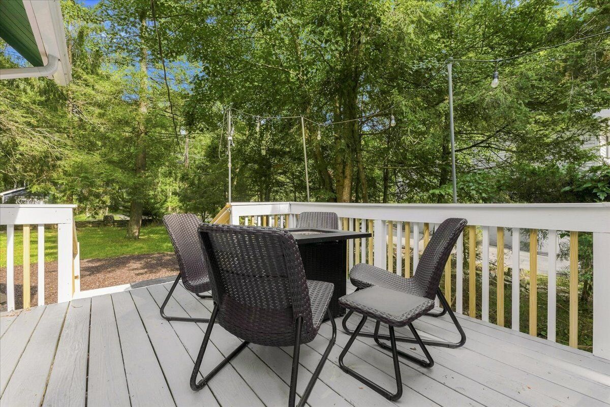 An outdoor deck with a table and chairs, surrounded by trees.