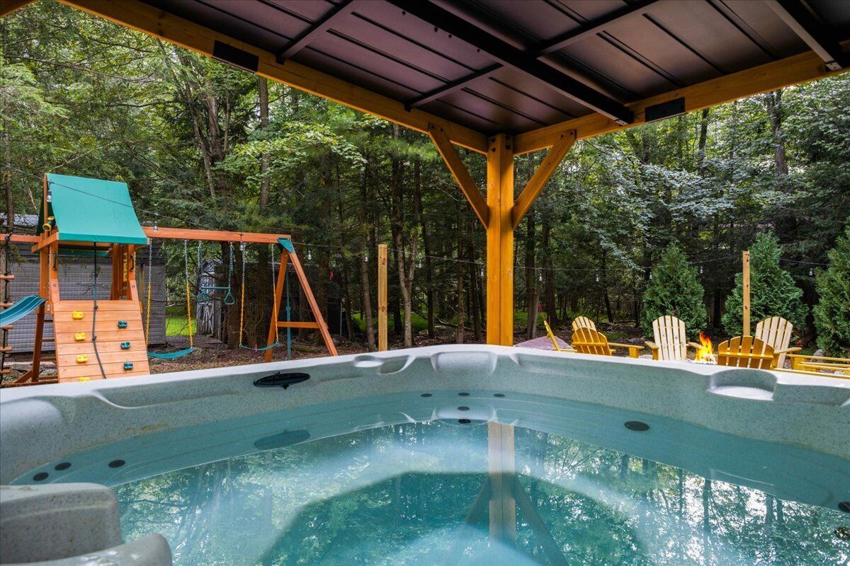 Ein Whirlpool mit einer Holzterrasse und einer Schaukel in einer bewaldeten Gegend.