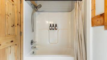 A shower with a wooden door, a showerhead, and a towel rack.